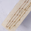 Rose gold and gold-colored necklaces with small regular beads placed along its length, laid out on a beige surface.