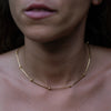 A woman wearing a gold necklace with little circle pendants.
