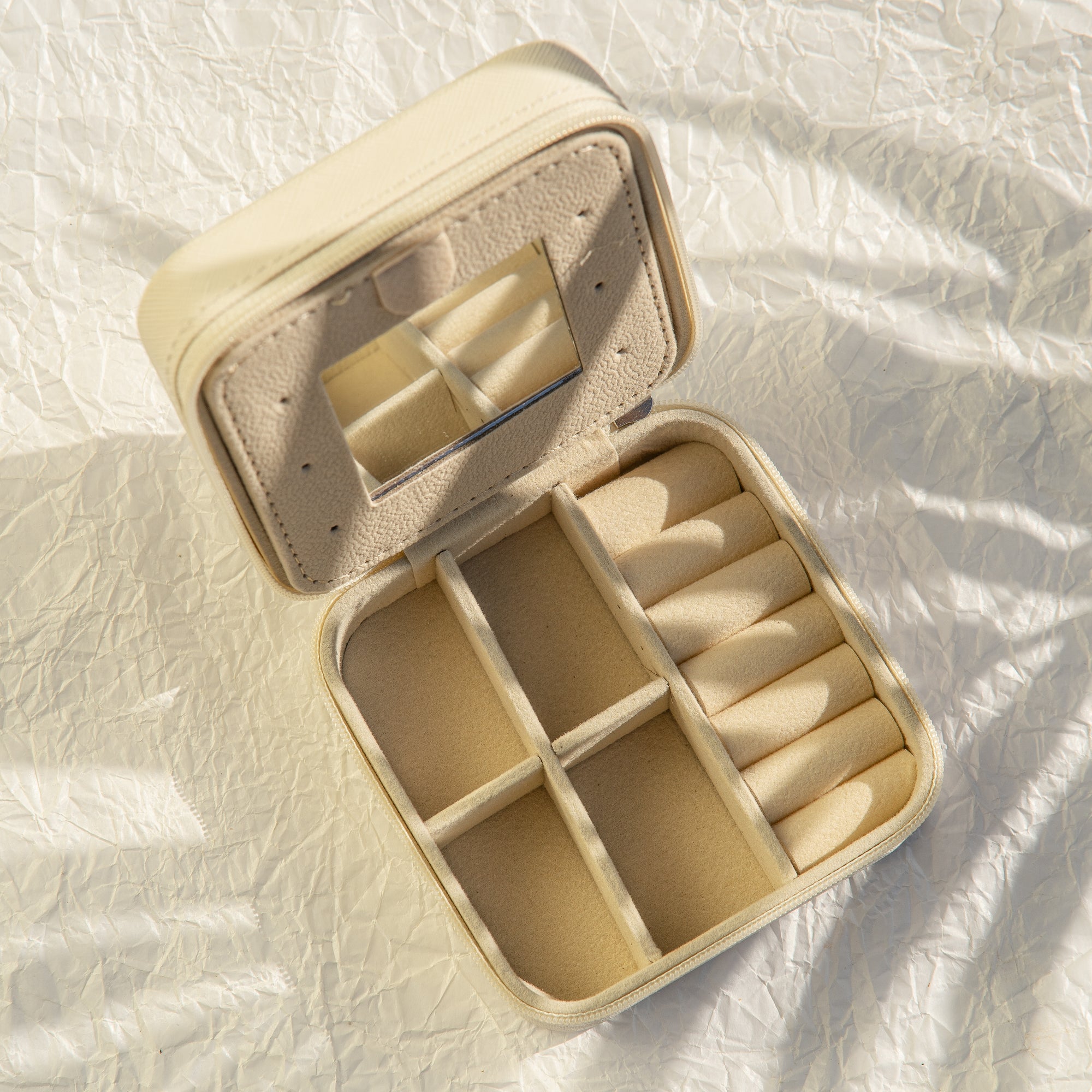 Beige jewellery box with compartments on a textured white surface