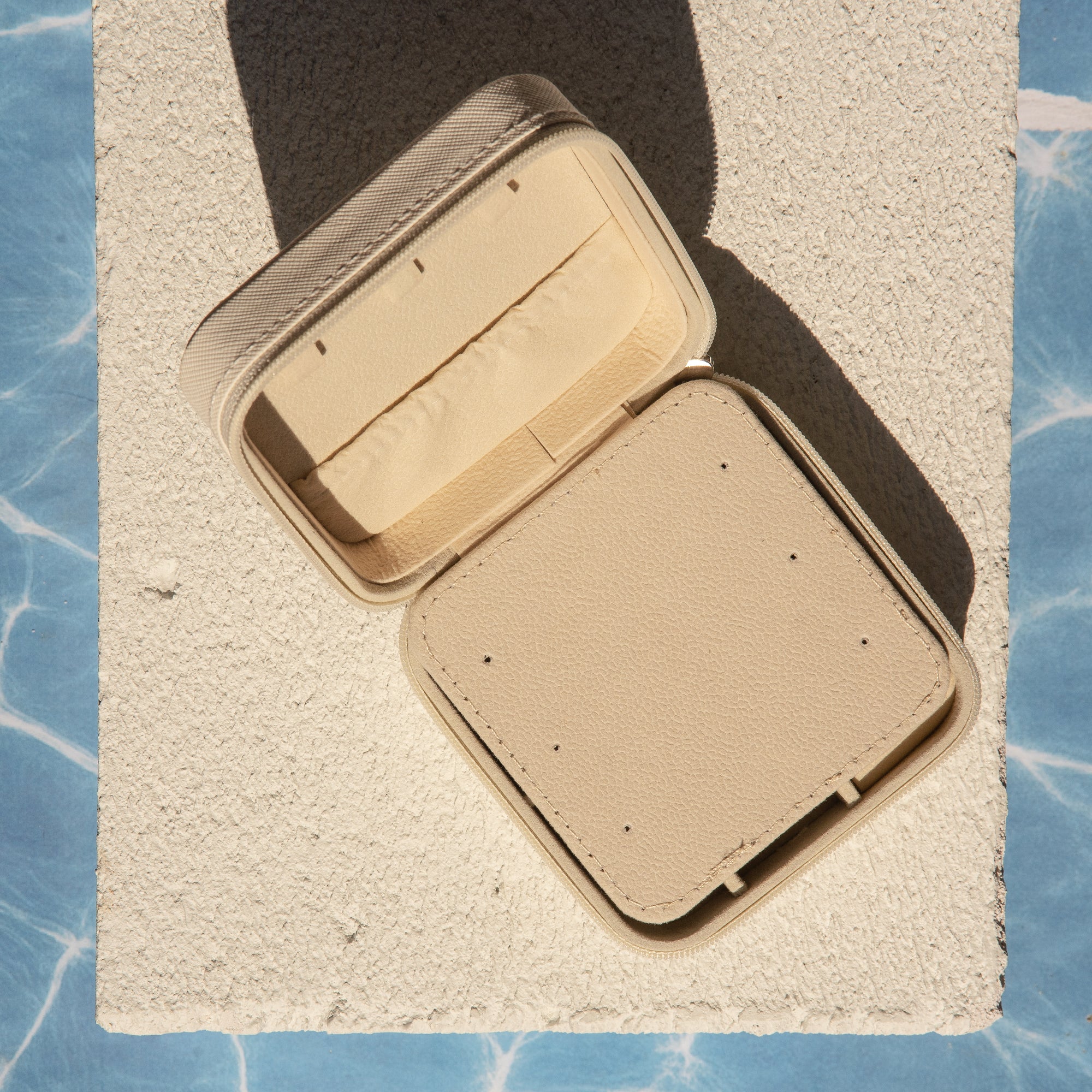 Beige jewellery case on a textured surface with blue pattern
