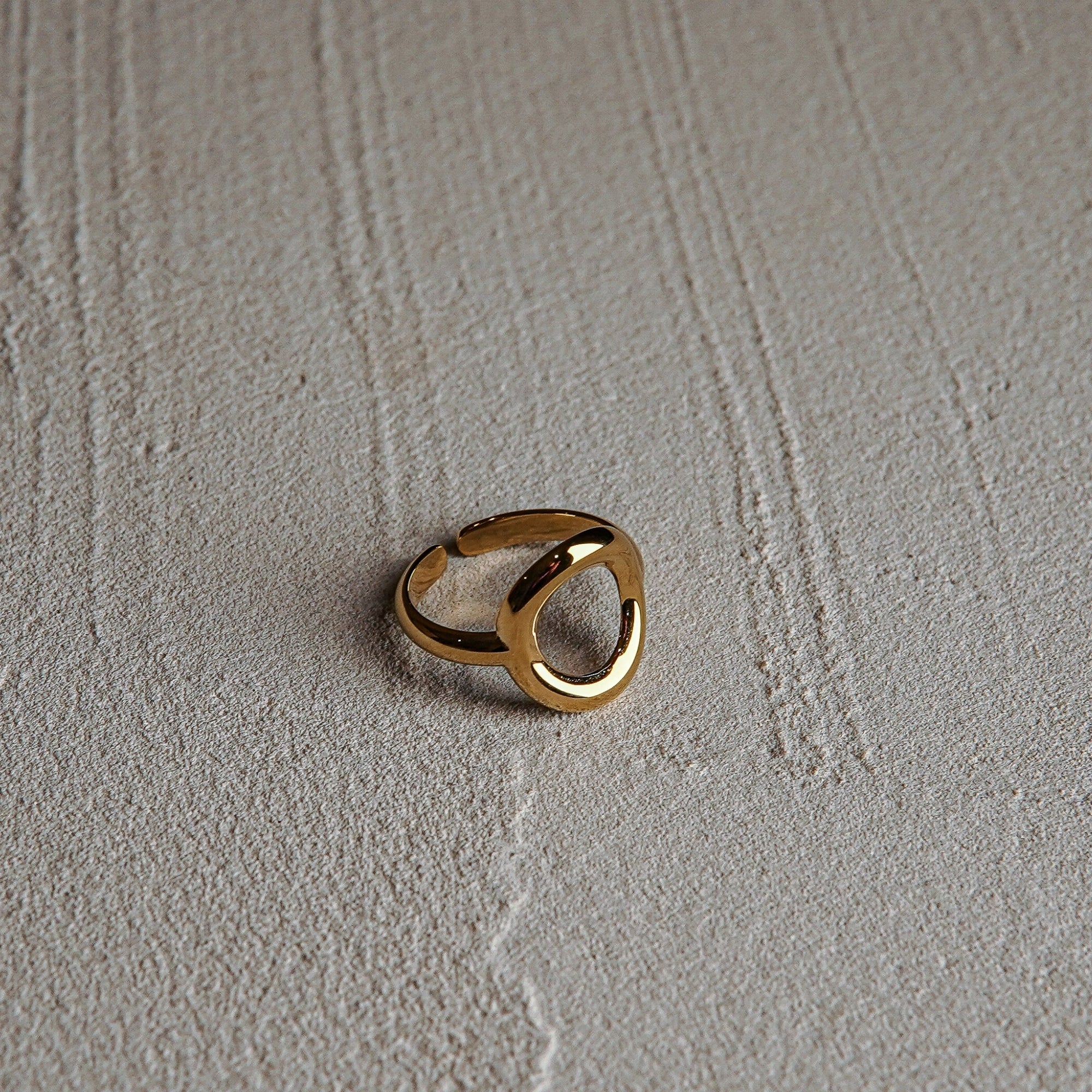 Gold ring on a textured beige surface