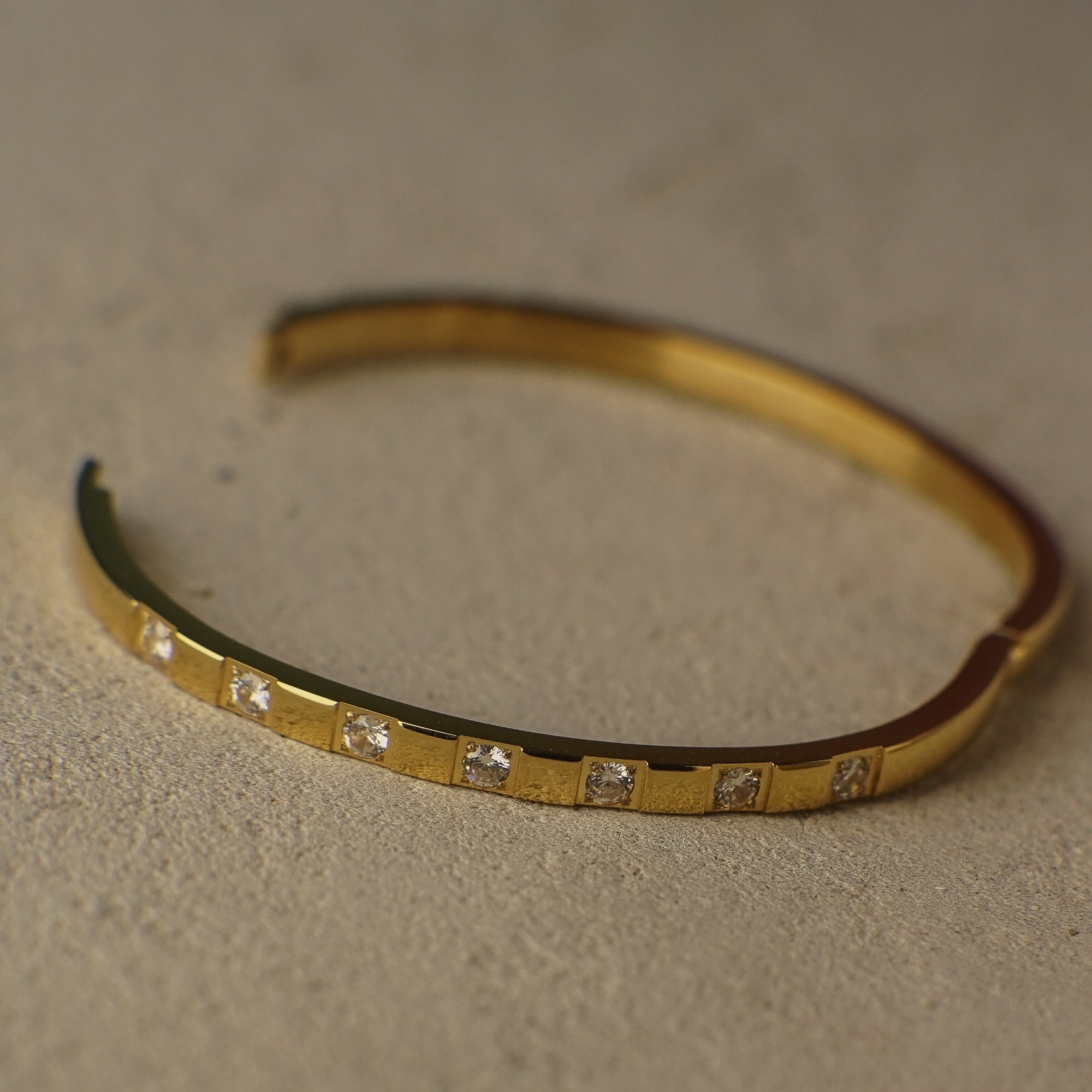 Gold bracelet with small diamonds on a beige background