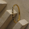 Gold bracelet with small diamonds on a beige stone surface