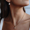 A model wearing a drop earring with cubic zirconia paired with gold necklace with the same design