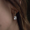 A model wearing a gold drop necklace with clear zirconia