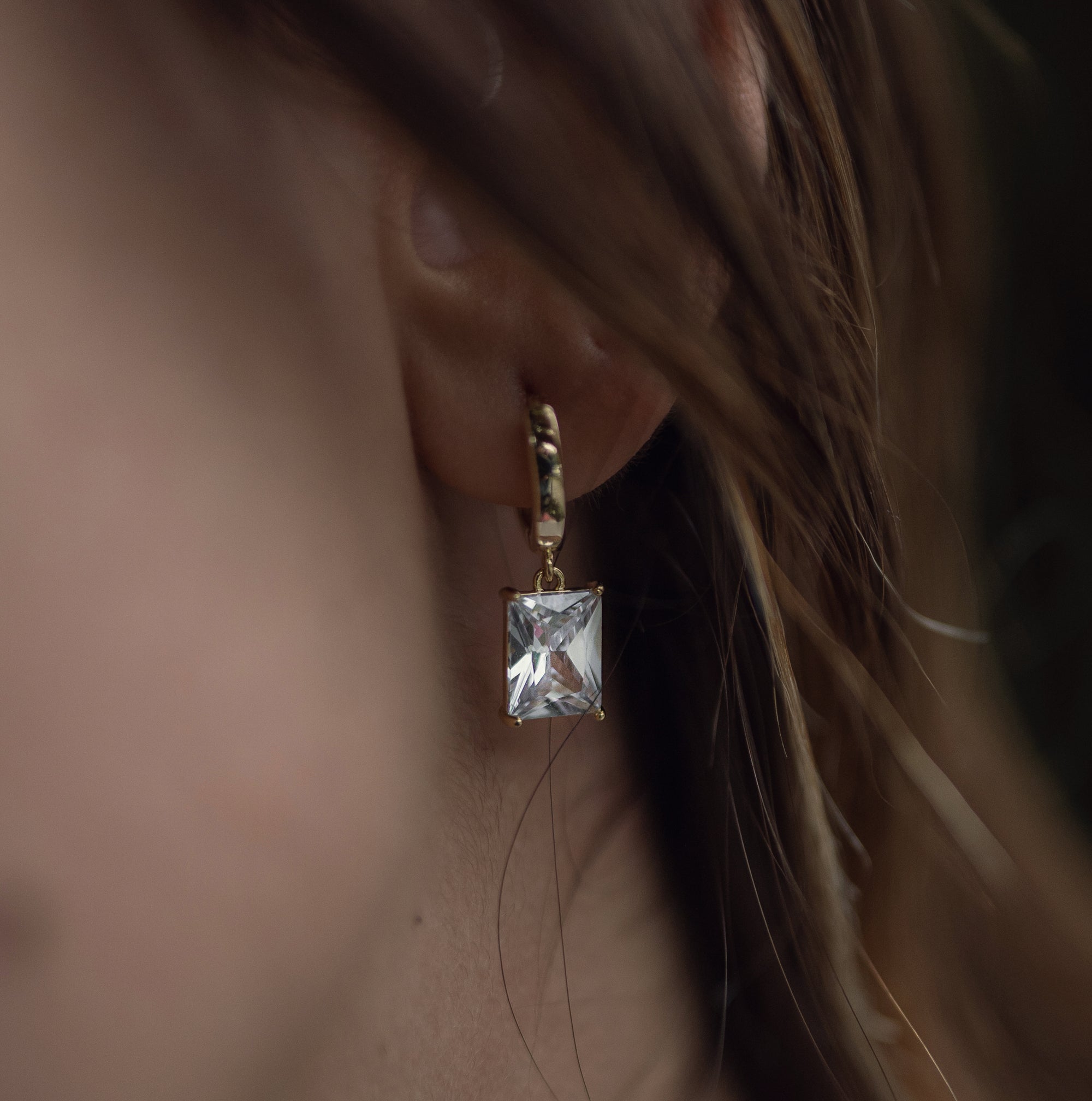 A model wearing a gold drop necklace with clear zirconia