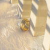 Gold ring on a textured beige surface with soft shadows