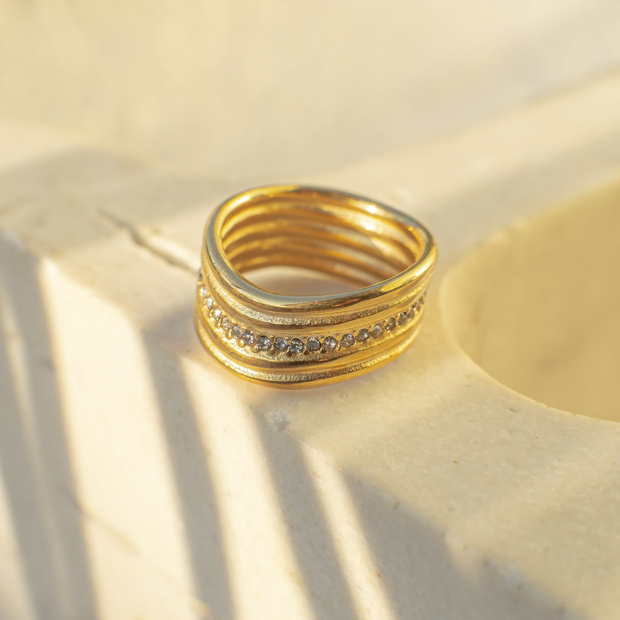 Gold ring with diamond accents on a beige surface