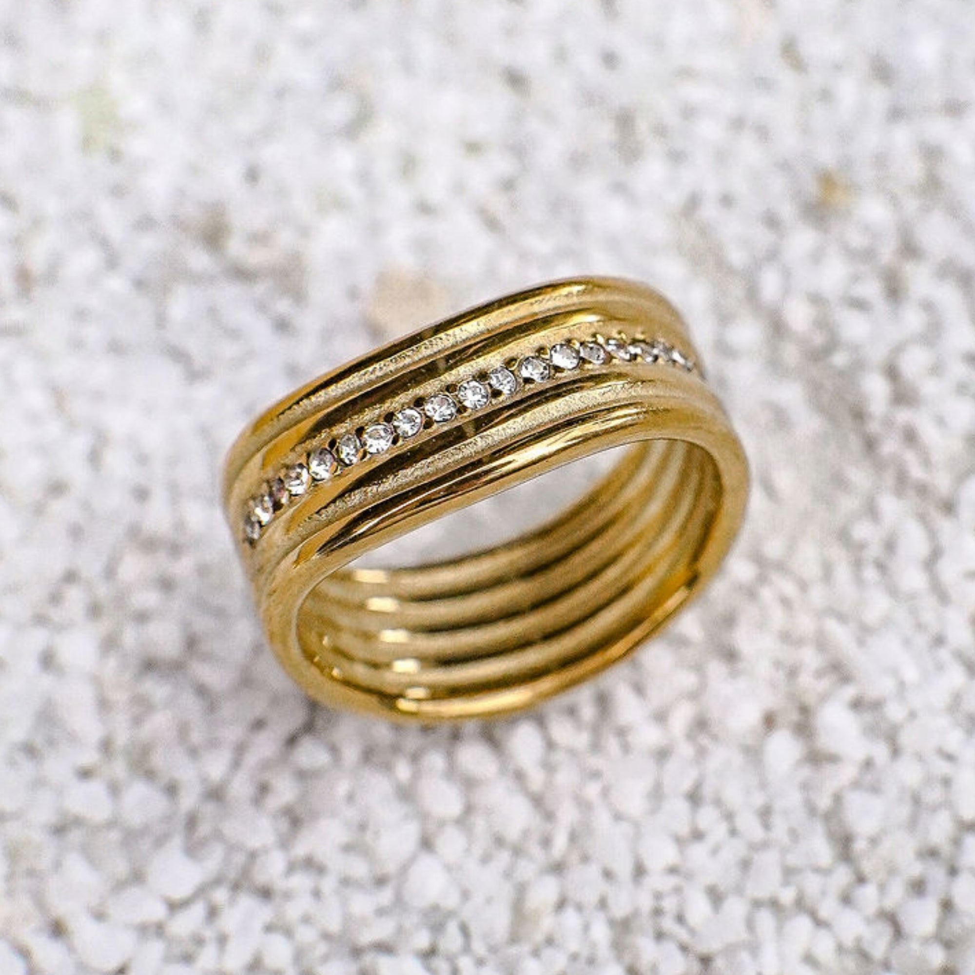 Gold ring with embedded diamonds on a textured white surface