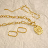 Gold chain necklace with a pendant on a textured beige background