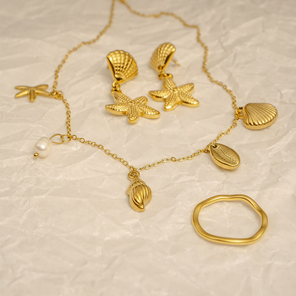 Gold jewelry set with necklace, earrings, and ring on a textured beige background