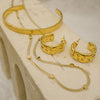 Gold jewelry set including hoop earrings and necklaces on a textured surface