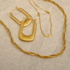 Gold hoop earrings and necklace on a textured beige surface