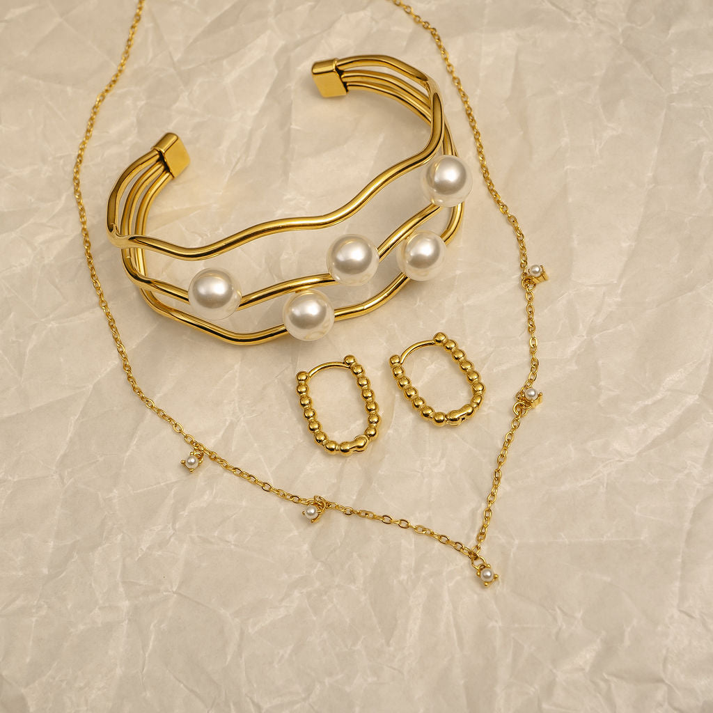 Gold jewelry set with pearls on a beige textured background