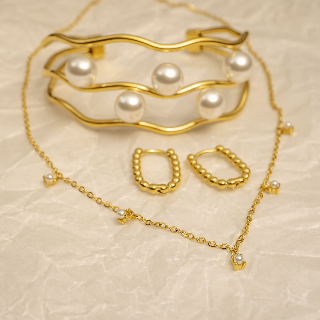 Gold jewelry set with pearls on a beige textured background