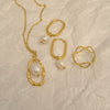Gold jewelry set with pearls on a textured beige surface