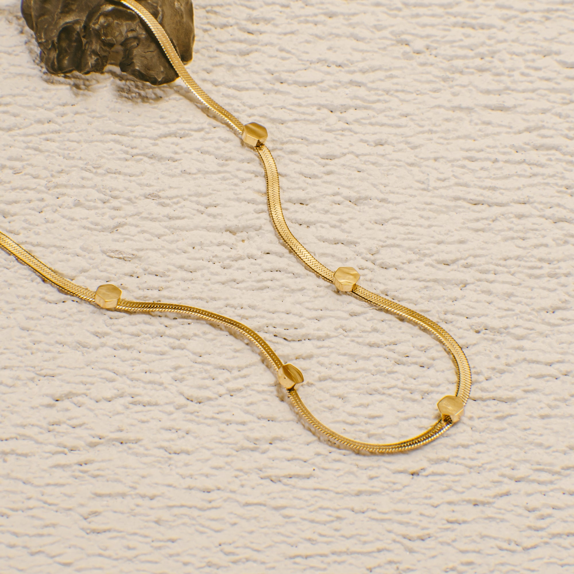 Gold necklace on a textured beige surface