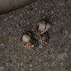 Pair of rose gold floral earrings on a textured surface