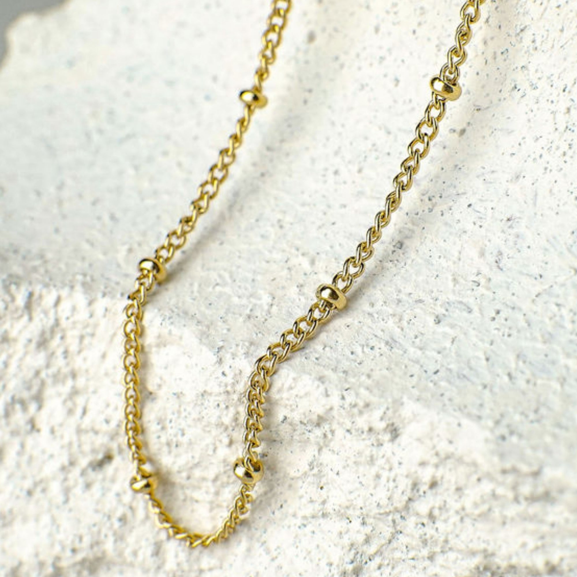 Gold chain necklace on a textured white surface