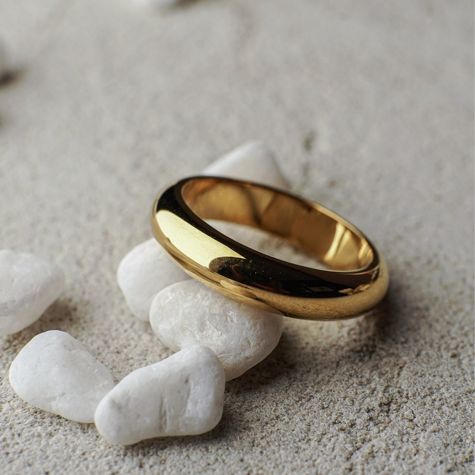 Gold ring on white pebbles with a natural background