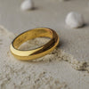 Gold ring on a sandy surface with small stones in the background