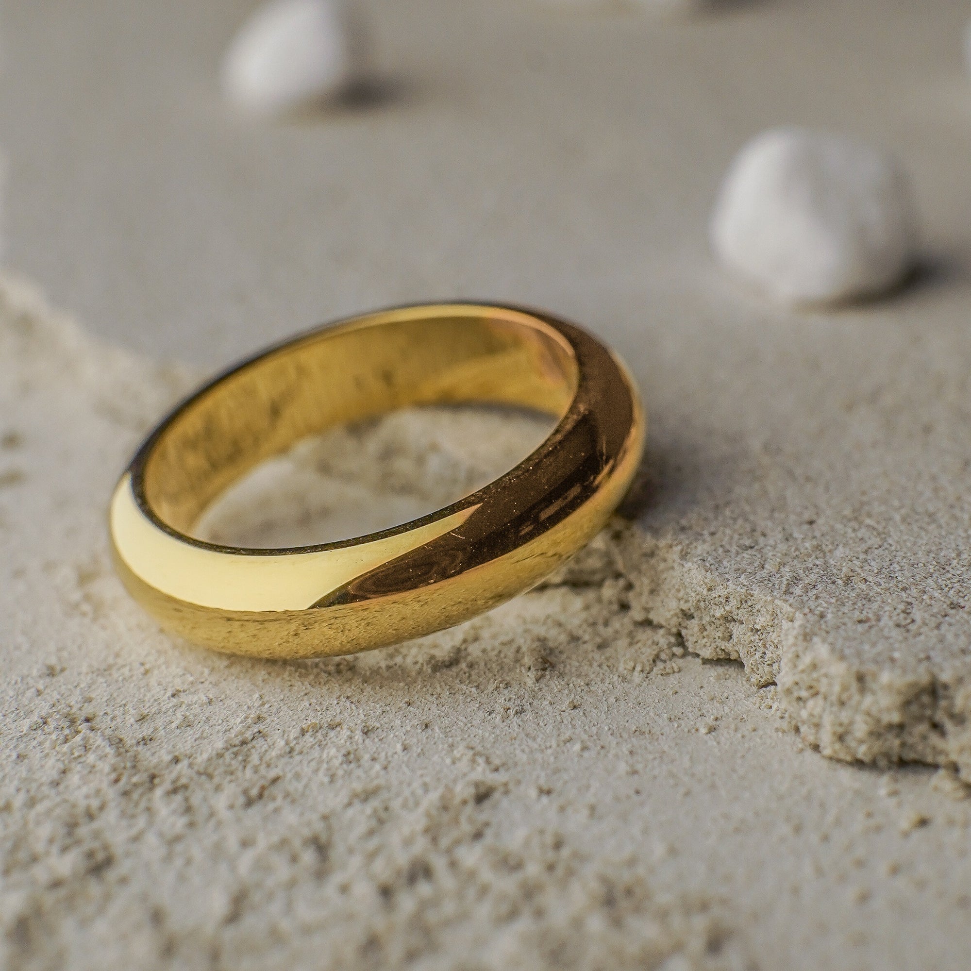 Gold ring on a sandy surface with small stones in the background