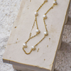 Gold chain necklace with pearls on a textured surface