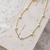 Gold necklace with pearls on a textured beige surface