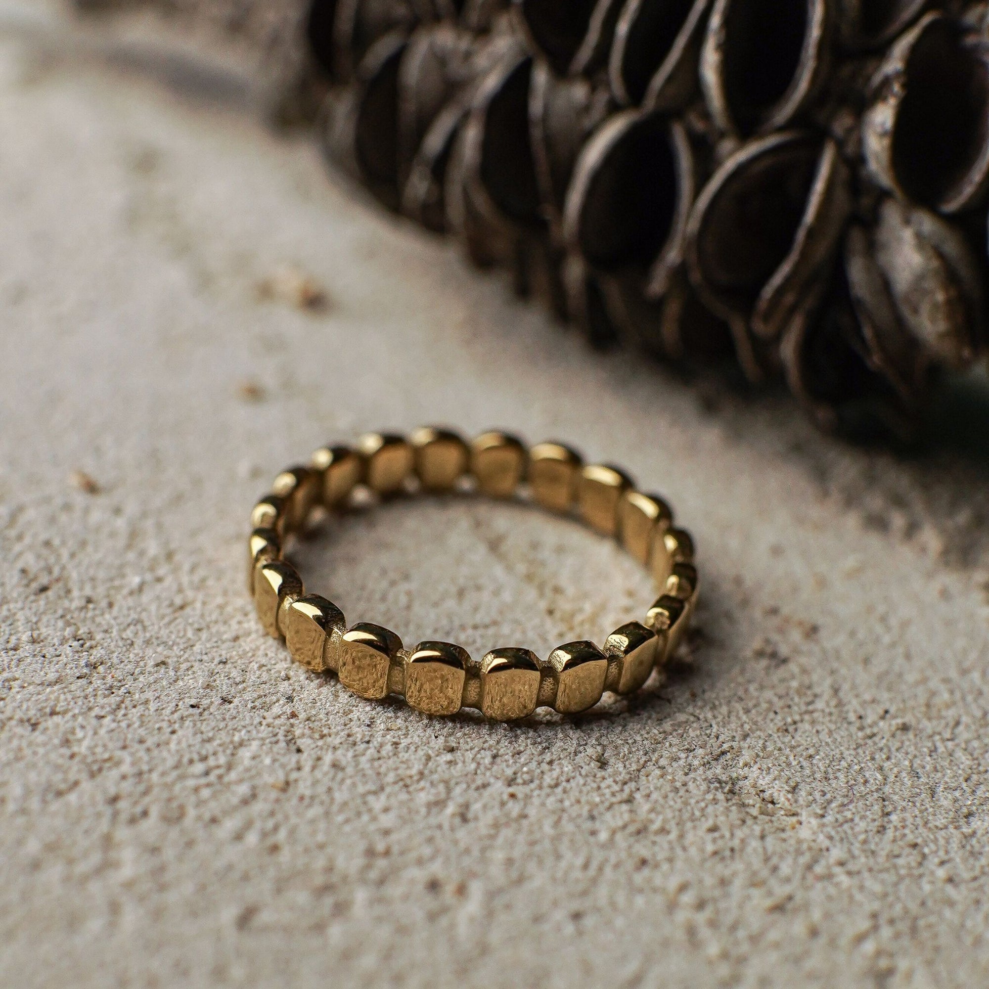 Gold ring on a textured surface with a dark woven object in the background