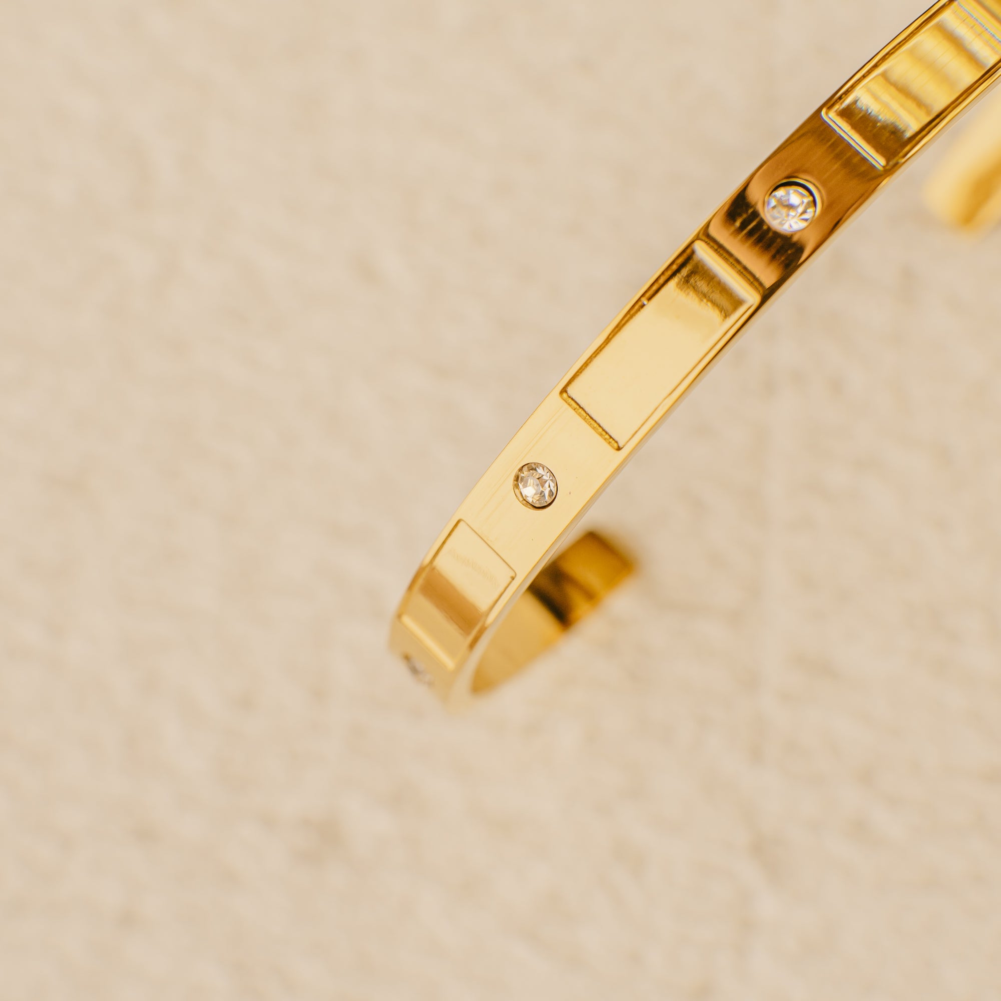 Gold bracelet with diamond accents on a beige background