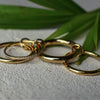 Three gold rings on a textured surface with green leaves in the background