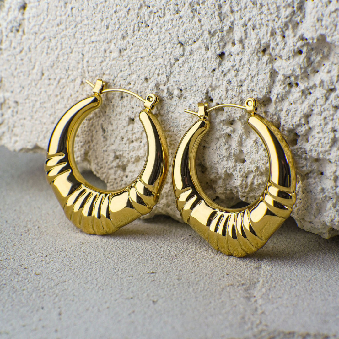 Gold hoop earrings on a textured stone surface
