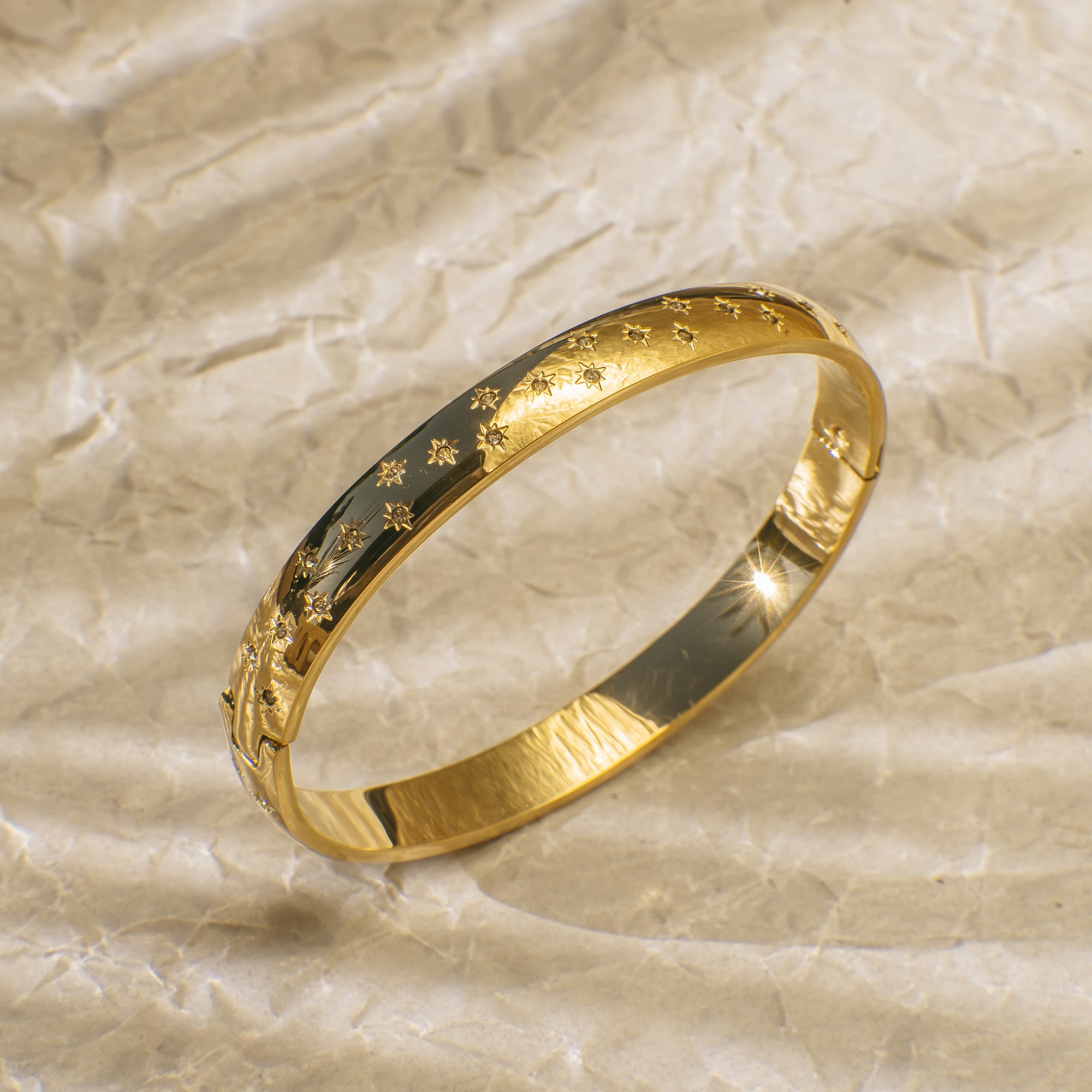 Gold bangle bracelet engraved with twinkling star designs.