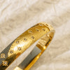 Gold bangle bracelet engraved with twinkling star designs.