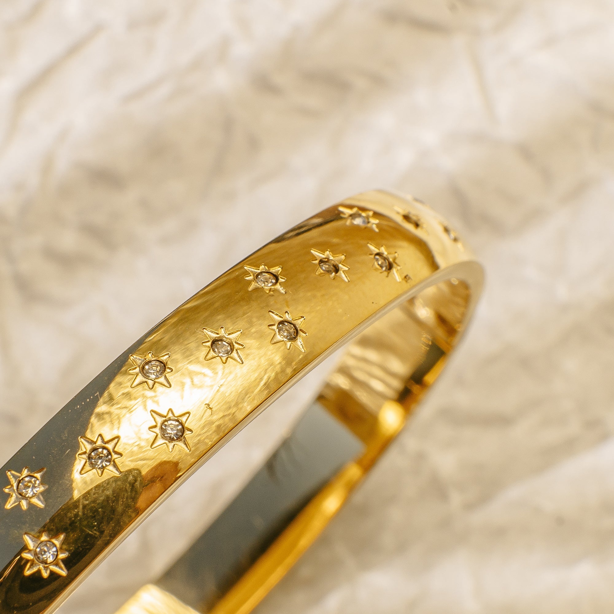 Gold bangle bracelet engraved with twinkling star designs.