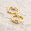 Gold hoop earrings with pearl accents on a light marble background