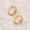 Gold hoop earrings with pearl-like beads on a beige marble surface