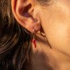 A model wearing a red chili gold earring
