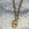 Gold necklace with a pendant on a textured gray surface