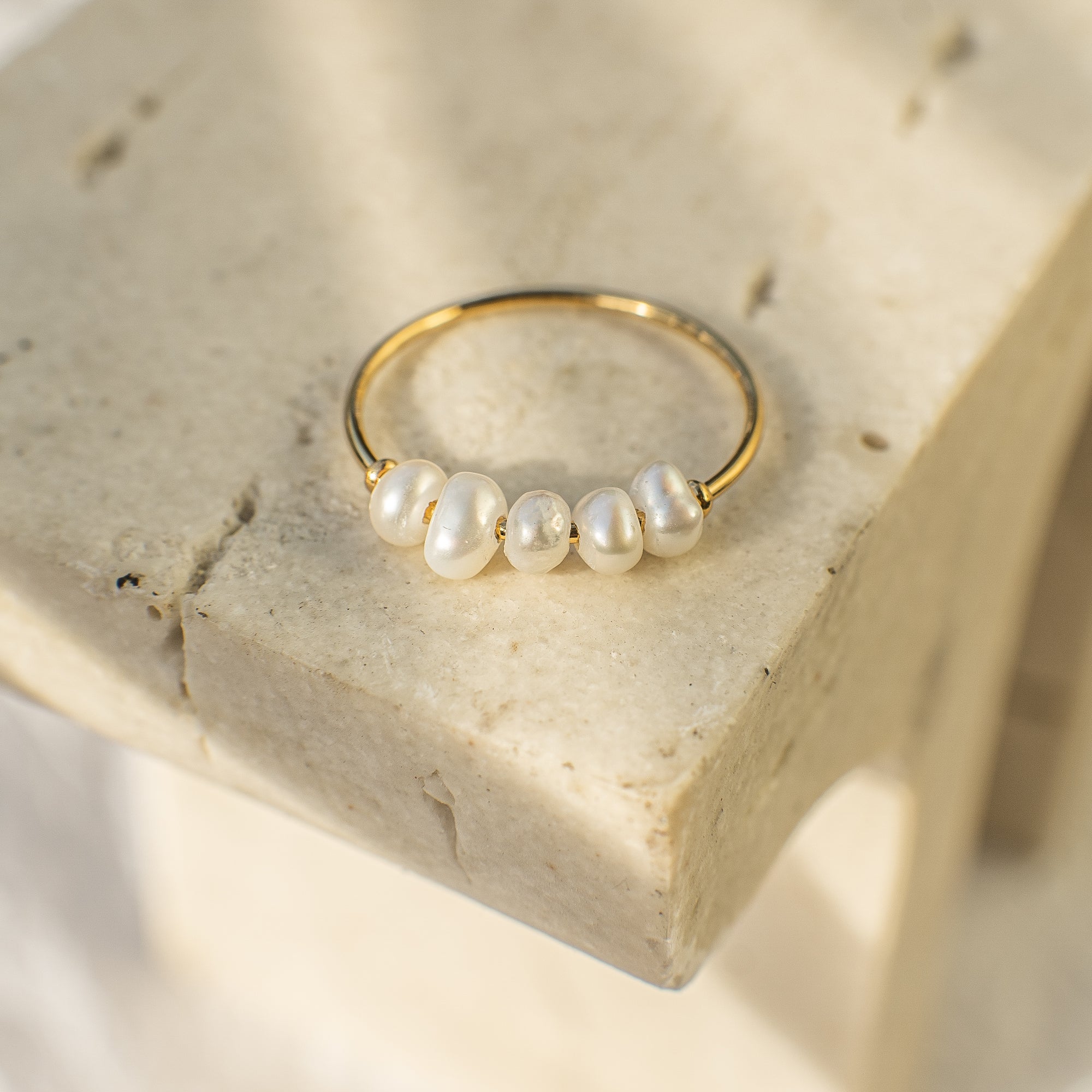 Gold ring with pearls on a textured stone surface