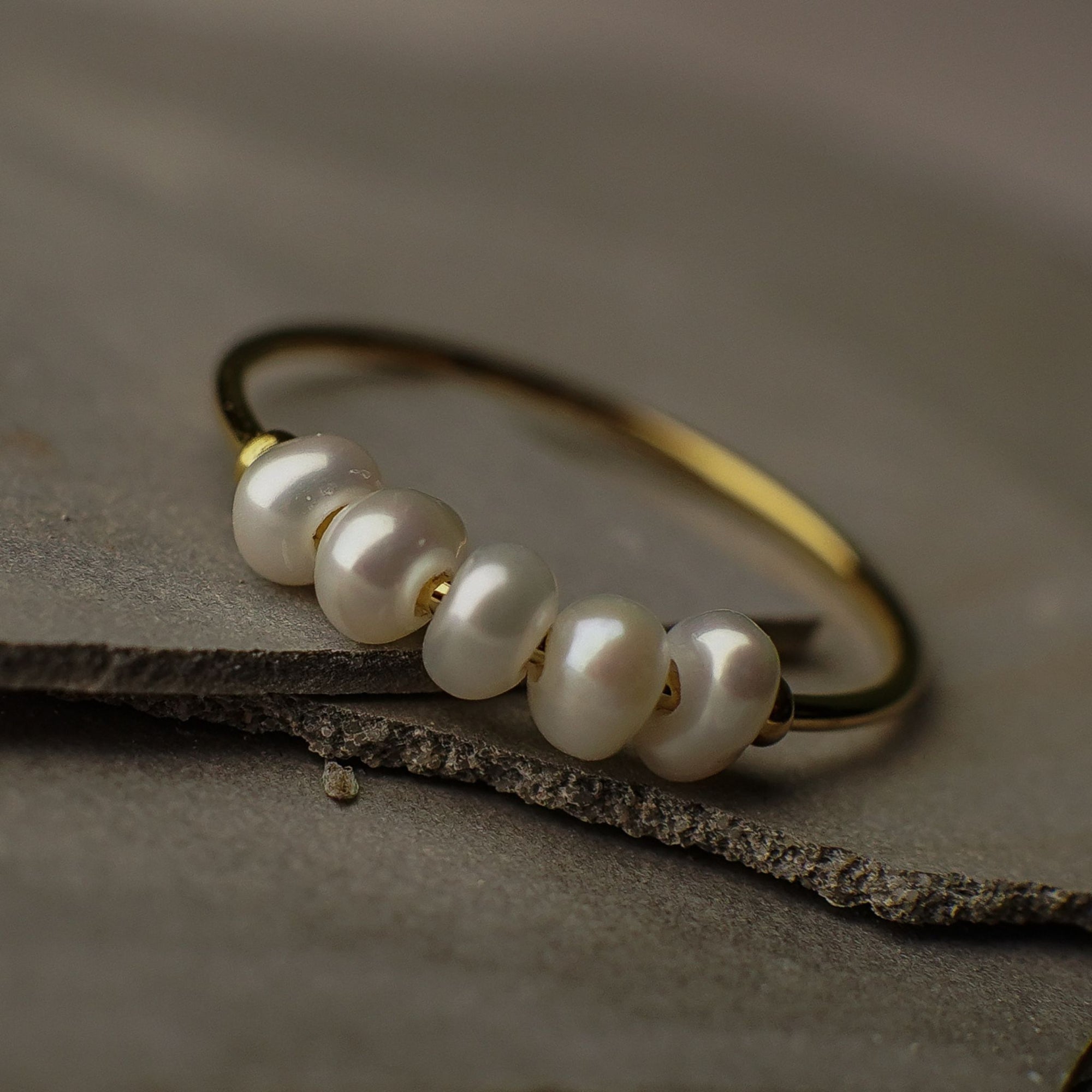 Gold ring with pearls on a textured surface