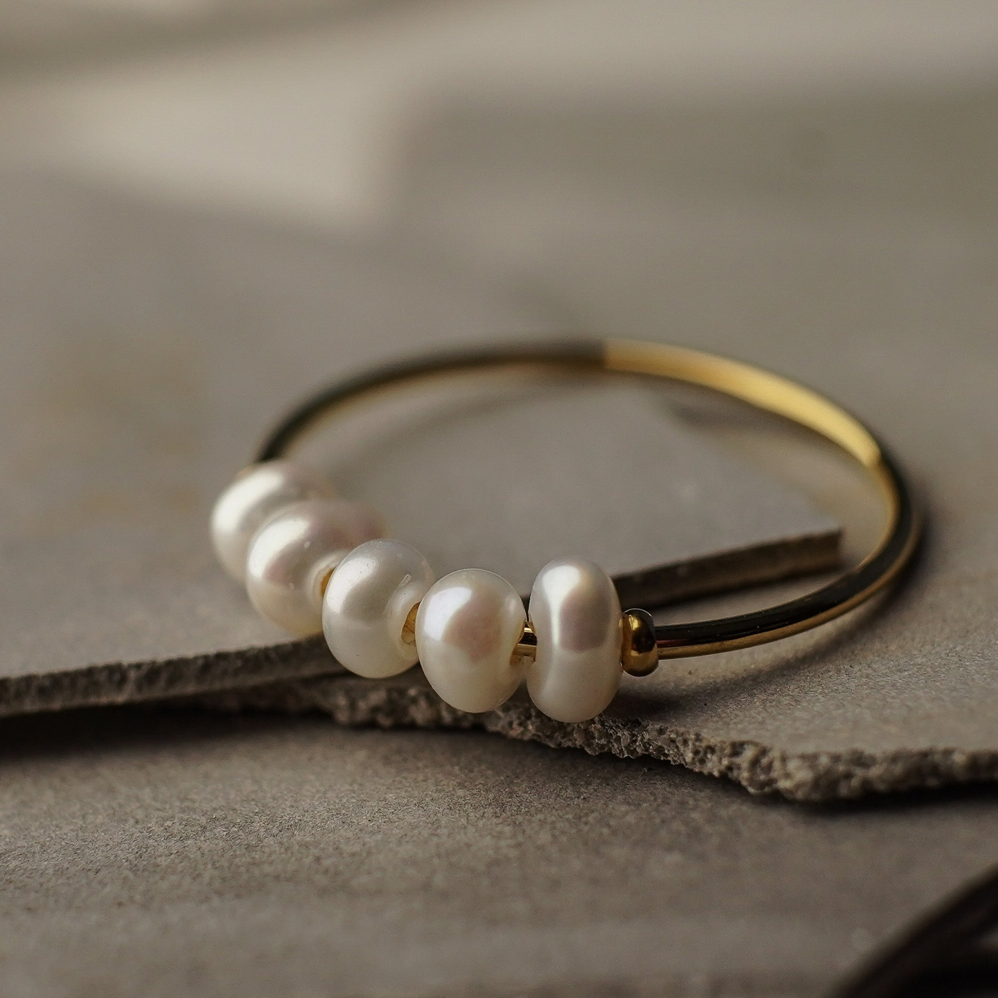 Pearl bracelet with gold accents on a textured surface