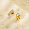Gold earrings with clear stones on a beige textured background