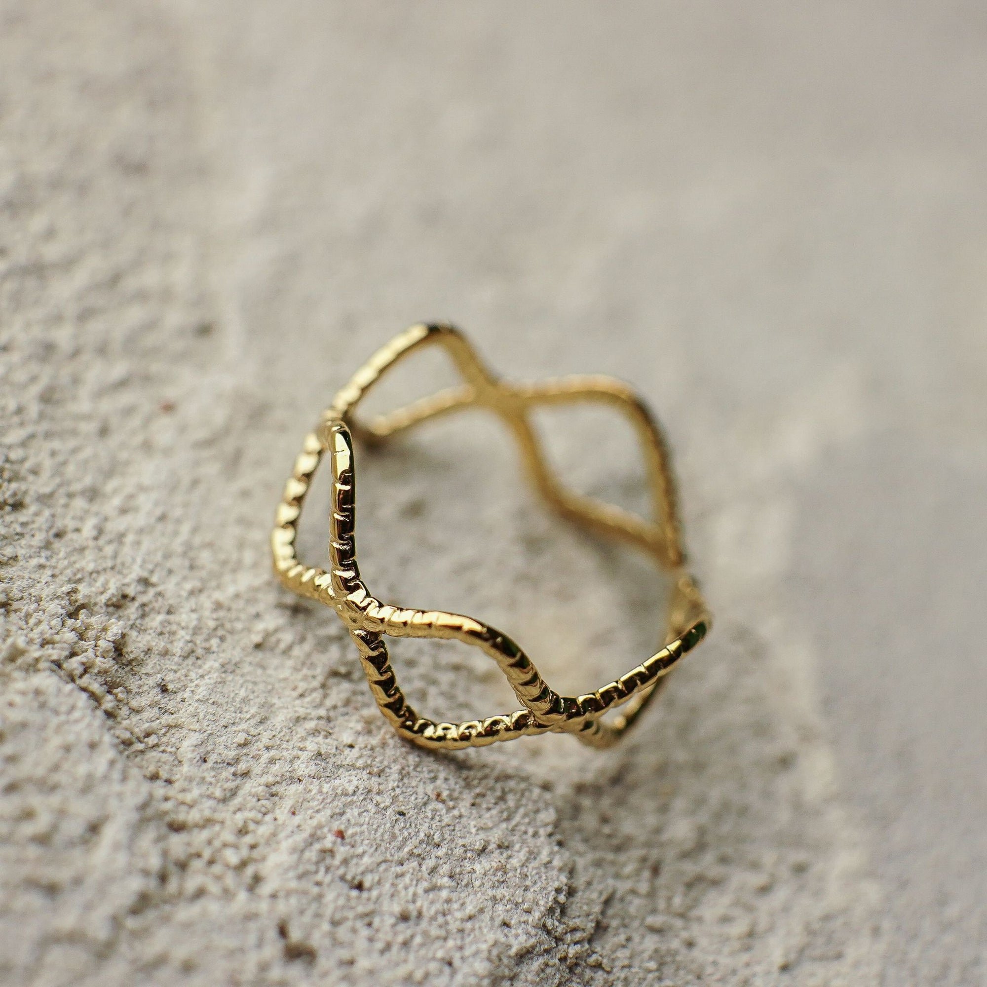 Gold ring with geometric design on a textured surface