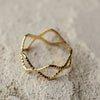 Gold ring with a textured design on a sandy background