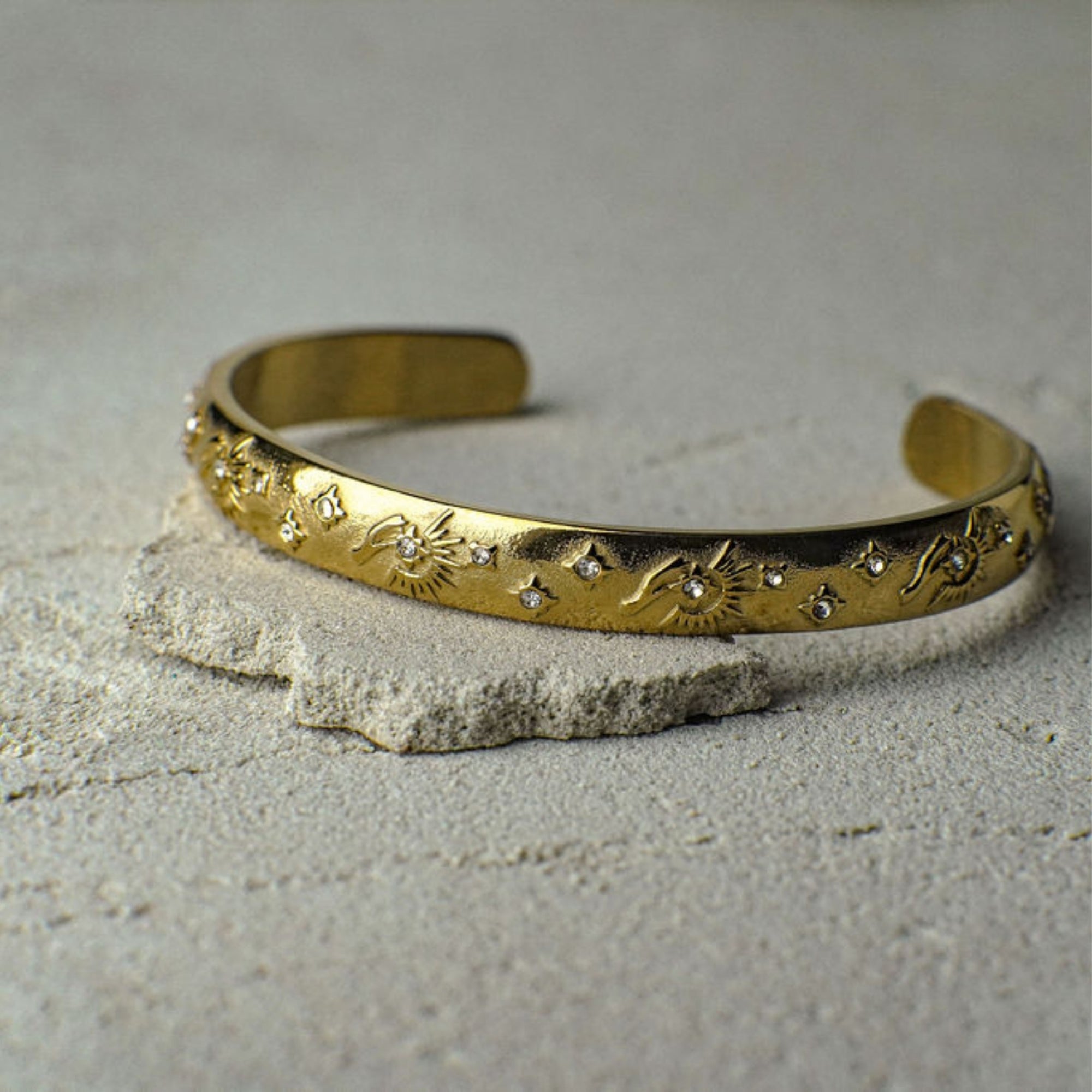 Gold bracelet with engraved design on a textured surface