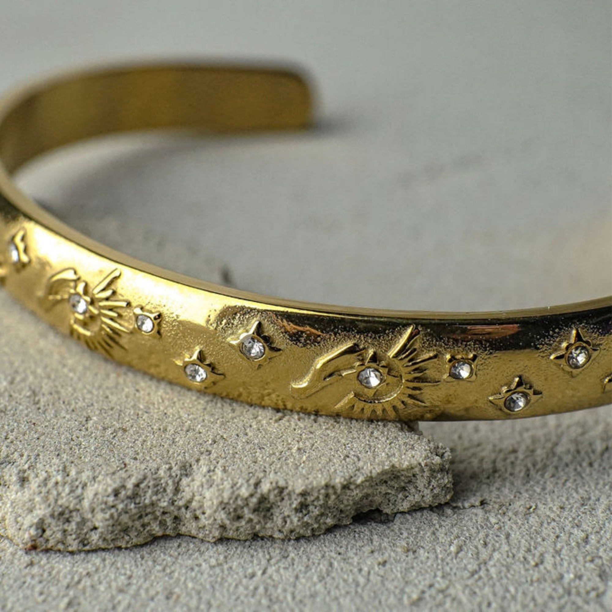 Gold headband with star and moon designs on a textured surface