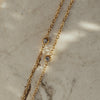 Dorota Zirconia Gold Necklace on beige textured surface