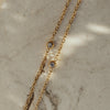 Dorota Zirconia Gold Necklace on beige textured surface