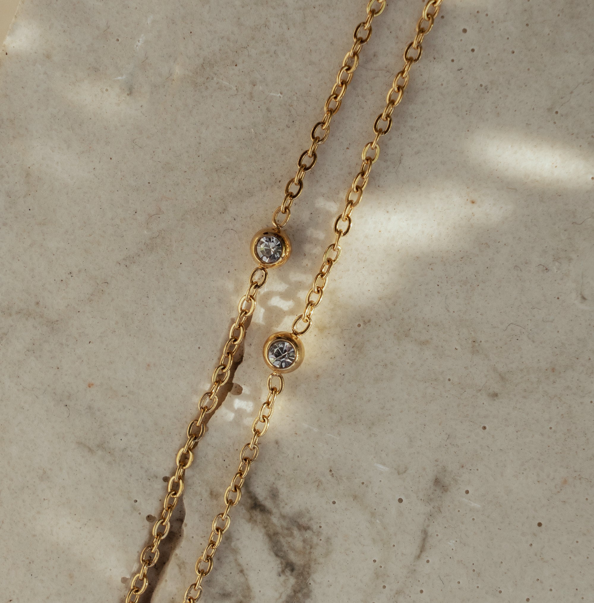 Dorota Zirconia Gold Necklace on beige textured surface